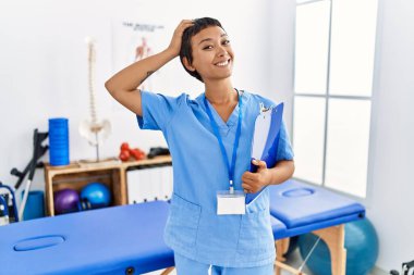 Kısa saçlı, İspanyol bir kadın ağrı kesici kliniğinde çalışıyor. Kendine güvenen, el hareketleriyle saçlara dokunan, çekici ve modaya uygun poz veren. 