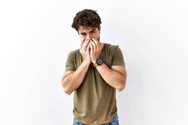 Hispanik adam izole edilmiş beyaz arka planda duruyor gülüyor ve utanıyor kıkırdıyor elleriyle ağzını kapatıyor, dedikodu ve skandal kavramı. 