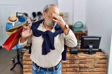 Butik dükkanında alışveriş poşetleri tutan yakışıklı bir adam. Pis ve iğrenç bir koku alıyor. Dayanılmaz bir koku. Kötü kokuyor. 