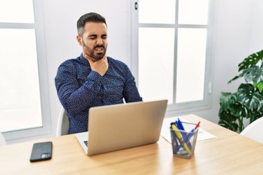 Ofiste sakallı, laptopuyla çalışan, boynu ağrıyan, grip, mantar ve enfeksiyon yüzünden boğaz ağrıyan genç bir İspanyol. 