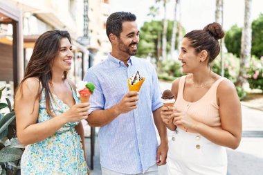 Üç İspanyol arkadaş gülerek şehirde dondurma yiyor..