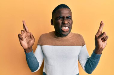 Genç Afro-Amerikalı sıradan kıyafetler giyen, umut ve gözlerin kapalı bir şekilde gülümseyerek el işareti yapan genç bir adam. Şans ve batıl inançlar. 