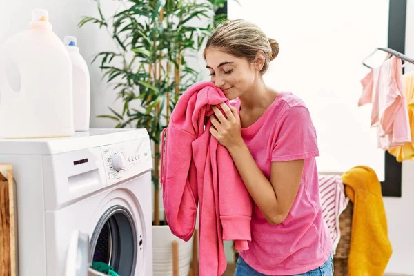 年轻的高加索女人在洗衣房闻到衣服的味道 — 图库照片