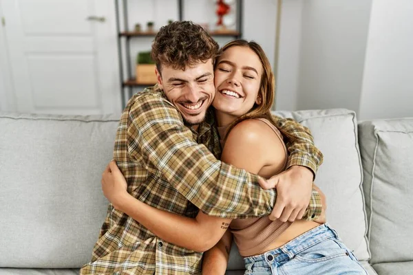 Jovem Casal Hispânico Sorrindo Feliz Abraçando Sentado Sofá Casa — Fotografia de Stock