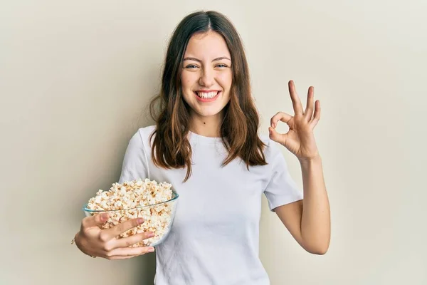 Young Brunette Woman Eating Popcorn Doing Sign Fingers Smiling Friendly — Fotografia de Stock