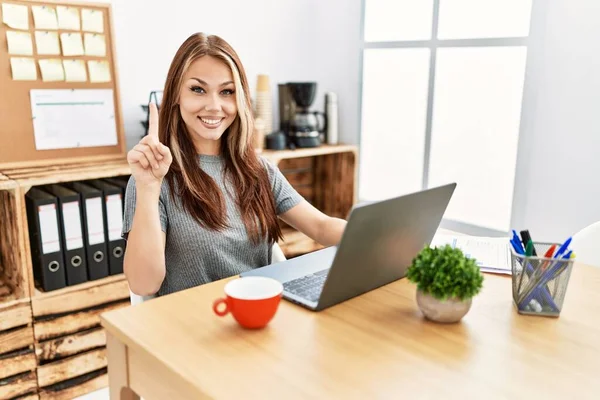 在办公室工作的年轻黑发女人 带着笔记本电脑 带着第一指尖 面带微笑 自信而快乐 — 图库照片