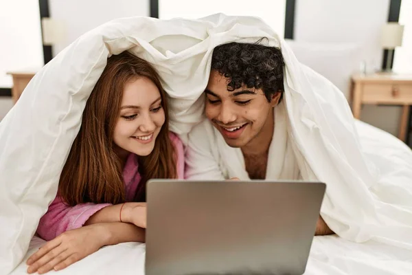 年轻夫妇躺在卧室的床上看电影 — 图库照片