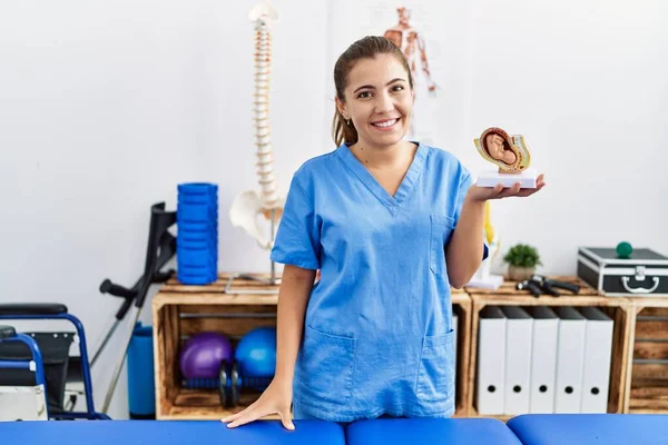 Jovem Hispânica Vestindo Fisioterapia Uniforme Segurando Modelo Anatômico Útero Centro — Fotografia de Stock