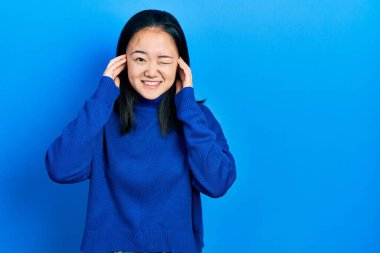 Gürültülü müzik sesi için kulaklarını parmaklarıyla kapatan sıradan kıyafetler giyen genç Çinli bir kız. sağır kavramı. 