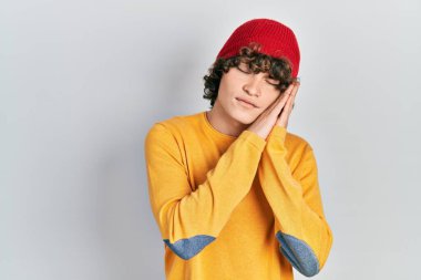 Yakışıklı, yün şapka takan, uyuyan, yorgun ve ellerinle poz veren ve gözleri kapalı gülümseyen genç adam.. 