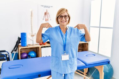 Orta yaşlı sarışın kadın ağrı kesici kliniğinde çalışıyor. Kendine güveni tam görünüyor. Kendini gururlu ve mutlu gösteriyor.. 