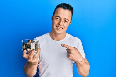 Elinde çiğ fındık tutan yakışıklı genç adam gülümseyerek mutlu bir şekilde elini ve parmağını gösterdi. 