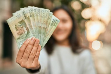 Orta Doğulu genç kız gülümsüyor Şili pesolarını şehirde tutuyor..