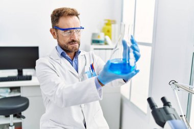 Laboratuvarda deney tüpü tutan orta yaşlı İspanyol üniformalı bir bilim adamı.