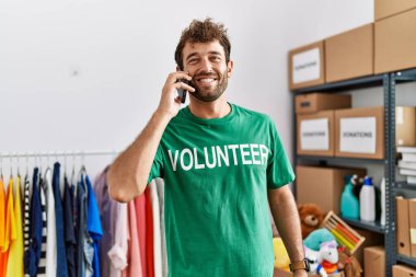 Genç İspanyol gönüllü adam gülümsüyor. Yardım merkezindeki akıllı telefondan konuşuyor..