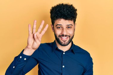 Sakallı, günlük gömlekli genç bir Arap dört numarayı gösterip işaret ederken kendinden emin ve mutlu bir şekilde gülümsüyor.. 