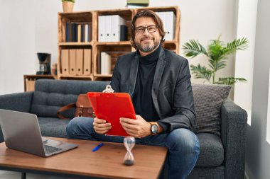 Muayenehanede çalışan yakışıklı, orta yaşlı bir adam yüzünde ciddi bir ifadeyle rahatlamış. Basit ve doğal bir şekilde kameraya bakıyorsun.. 