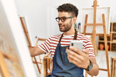 Sanat stüdyosunda akıllı telefon çizimi yapan genç bir Arap sanatçı..