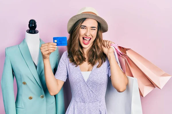 Young Hispanic Girl Holding Shopping Bags Credit Card Winking Looking — Stock fotografie