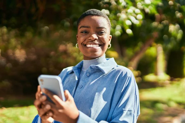 若いアフリカ系アメリカ人の女性が市内のスマートフォンを使って笑顔で — ストック写真
