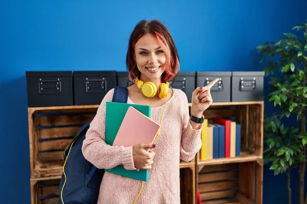 若いですCaucasian女性身に着けて学生のバックパックと本笑顔幸せなポインティングとともに手と指で側面 — ストック写真