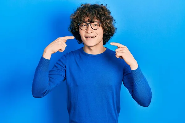 英俊的年轻人穿着休闲装 戴着眼镜 笑容满面 用手指 牙齿和嘴指指点点 牙齿健康概念 — 图库照片