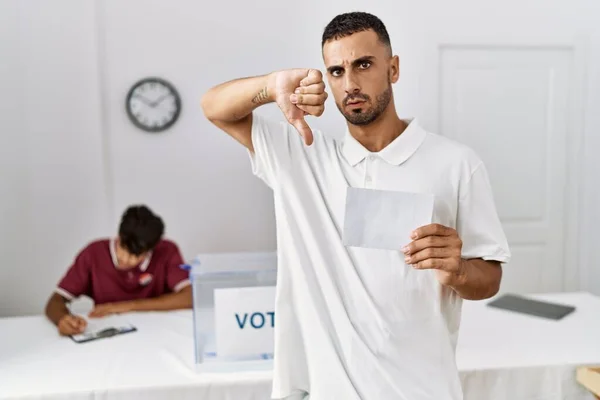 Jovem Hispânico Votando Colocando Envoltório Urna Com Cara Irritada Sinal — Fotografia de Stock