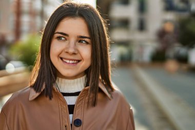 Genç, güzel, esmer kadın dışarıda mutlu bir şekilde gülümsüyor.