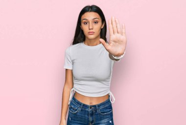 Gündelik beyaz tişört giyen genç İspanyol kız avuç içiyle şarkı söylemeyi kesiyor. Yüzünde olumsuz ve ciddi bir jest olan uyarı ifadesi. 