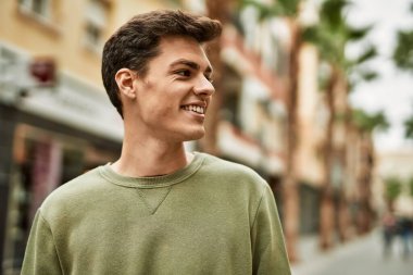 Genç İspanyol adam gülümseyerek şehirde mutlu mesut dikiliyor..