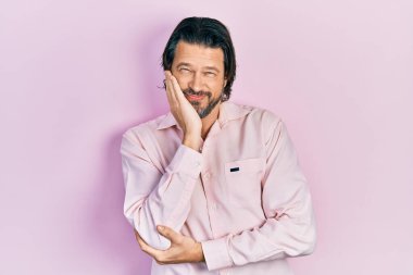 Orta yaşlı, günlük kıyafetler giyen, yorgun görünen ve depresyondan sıkılmış kollarını kavuşturan beyaz bir adam.. 