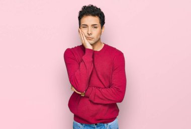 Gündelik kıyafetler giyen yakışıklı genç adam kollarını kavuşturarak depresyondan sıkılmış ve yorgun görünüyor.. 