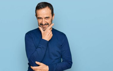 Orta yaşlı İspanyol bir adam gündelik kıyafetler giyiyor kameraya bakıyor kollarını kavuşturup gülümsüyor ve çenesini kaldırıyor. Olumlu düşünmek. 