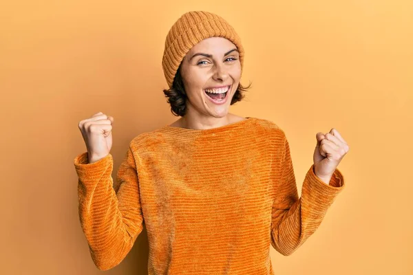 Genç esmer kadın yün şapka ve kışlık kazak giymiş gururla bağırıyor zaferi ve başarıyı kutluyor. 