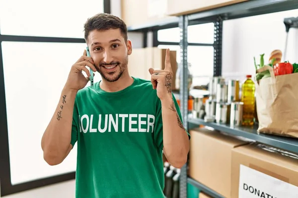 Joven Hispano Vistiendo Camiseta Voluntaria Hablando Por Teléfono Sonriendo Feliz — Foto de Stock