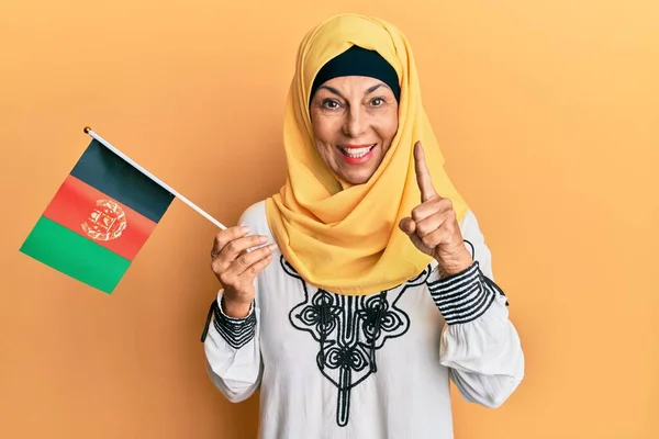 Hiszpanka Średnim Wieku Trzymająca Flagę Afganistanu Uśmiechnięta Pomysłem Lub Pytaniem — Zdjęcie stockowe
