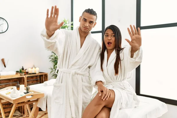 Young Latin Couple Wearing Towel Standing Beauty Center Doing Stop — Stockfoto