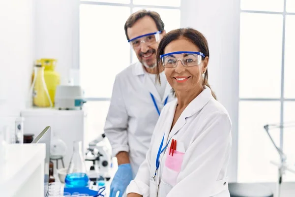 中年男人和女人穿着科学家制服 看着实验室里的摄像机 — 图库照片