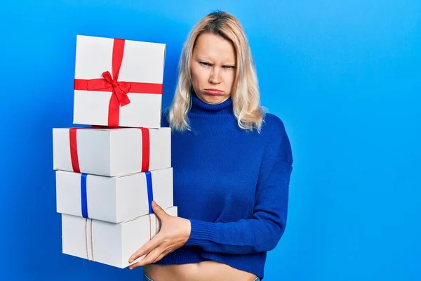 Beautiful Caucasian Blonde Woman Holding Gifts Skeptic Nervous Frowning Upset — Stock Photo, Image