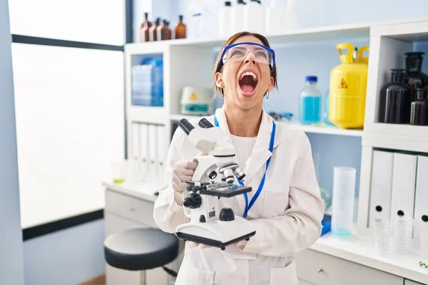 Young Brunette Woman Working Scientist Laboratory Microscope Angry Mad Screaming — Stock Photo, Image