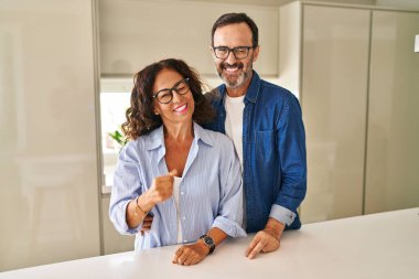 Orta yaşlı bir çift birlikte kameraya seksi bir ifadeyle, neşeli ve mutlu bir yüzle bakıyor.. 