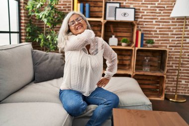 Orta yaşlı bir kadın koltuğunda oturup sırt ağrısı çekiyor.