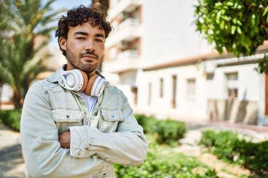 Yakışıklı, sakallı, neşeli, güneşli bir günde kulaklık takan bir İspanyol.