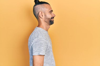 Latin kökenli genç adam rahat bir görünüm takınıyor, rahat bir görünüm takınıyor, kendine güvenen bir gülümsemeyle.. 