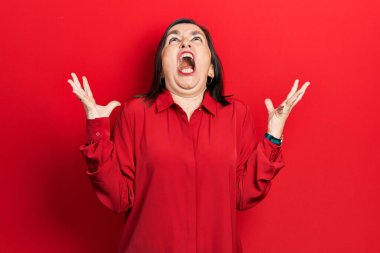 Orta yaşlı İspanyol kadın gündelik kıyafetler giyip deli gibi bağırıyor, agresif bir ifadeyle bağırıyor ve kollarını kaldırıyor. hüsran kavramı. 