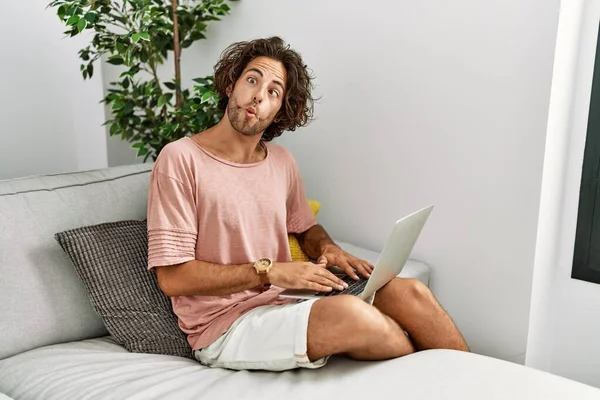 Evdeki Kanepede Dizüstü Bilgisayar Kullanarak Oturan Genç Spanyol Adam Dudaklarıyla — Stok fotoğraf