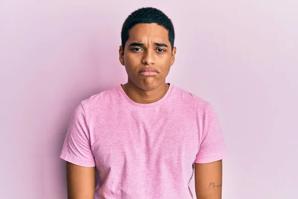 若いハンサムなヒスパニック系の男性がカジュアルなピンクのTシャツを着て落ち込んで苦痛を心配し 怒って恐れて泣いている 悲しい表情 — ストック写真