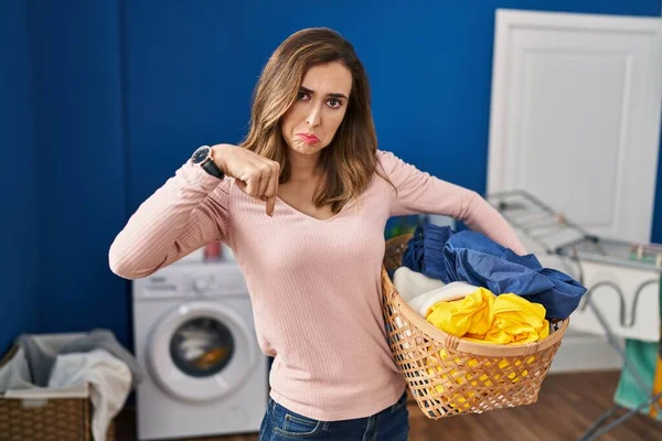 Young Woman Holding Laundry Basket Pointing Looking Sad Upset Indicating — ストック写真