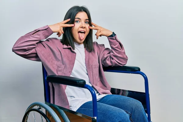 Молодая Брюнетка Сидящая Инвалидной Коляске Делает Символ Мира Пальцами Лице — стоковое фото