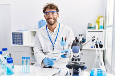 Laboratuvarda Loupe 'u kullanan İspanyol bir bilim adamı üniforması giyiyor.